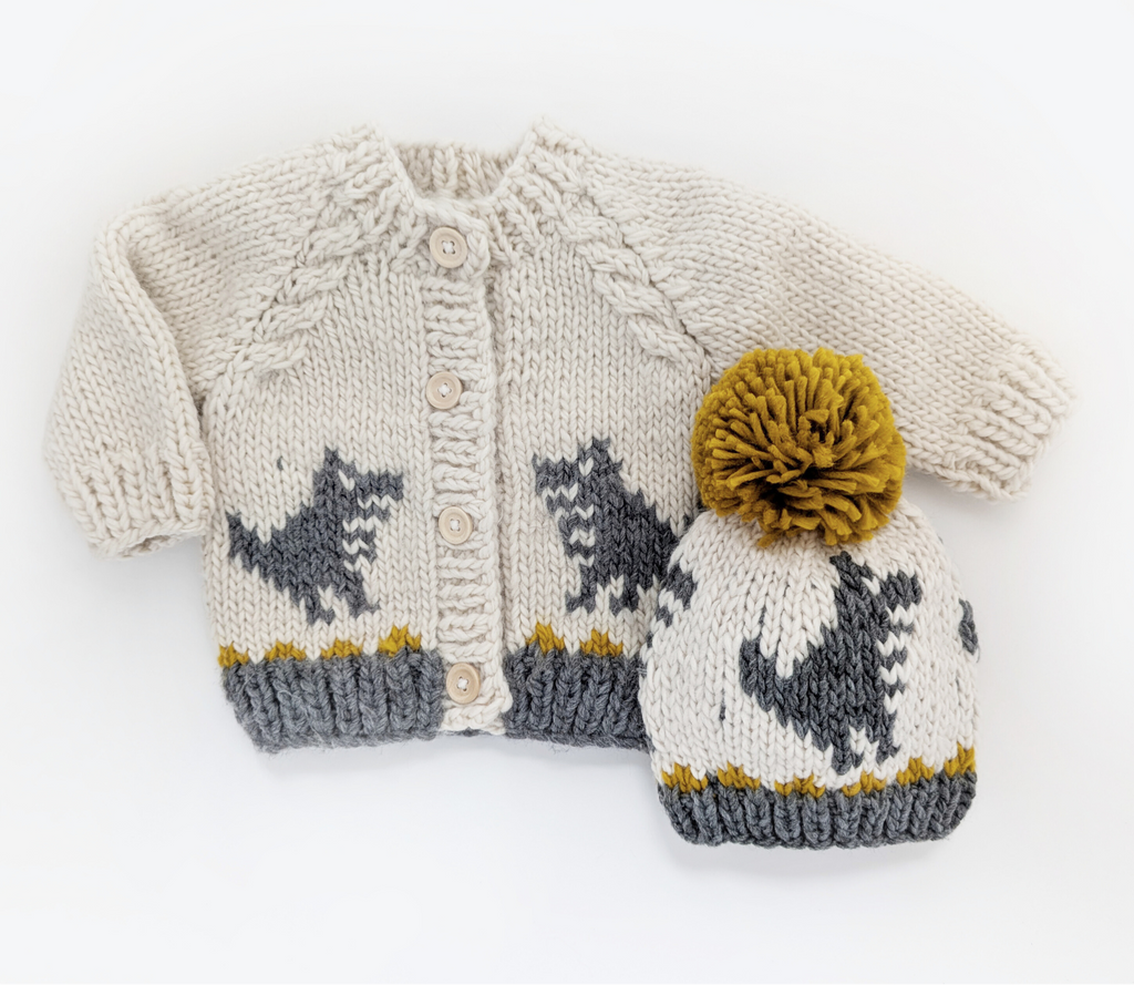 Knitted sweater and hat set with dinosaur pattern on a white background